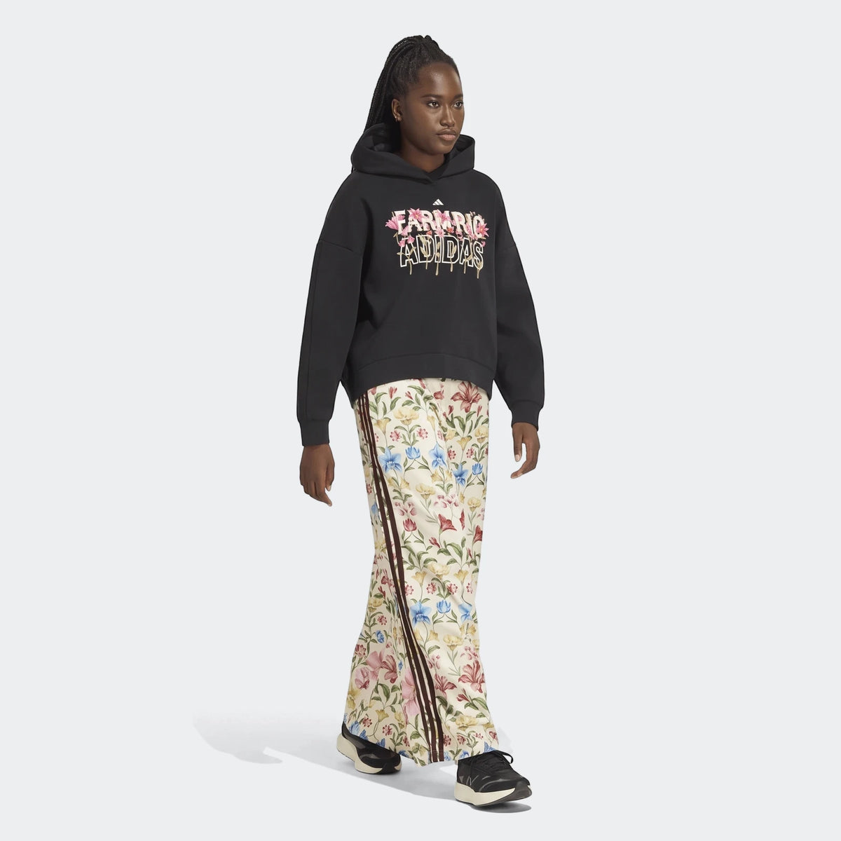 Female model wearing X Farm Rio Premium Joggers with a colorful floral print and a black Adidas hoodie with a vibrant floral