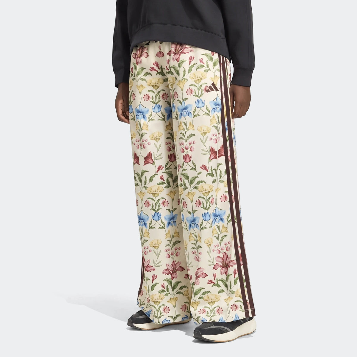 X Farm Rio Premium Joggers in a cream floral pattern, featuring dark brown side stripes and an Adidas logo, worn by a person.