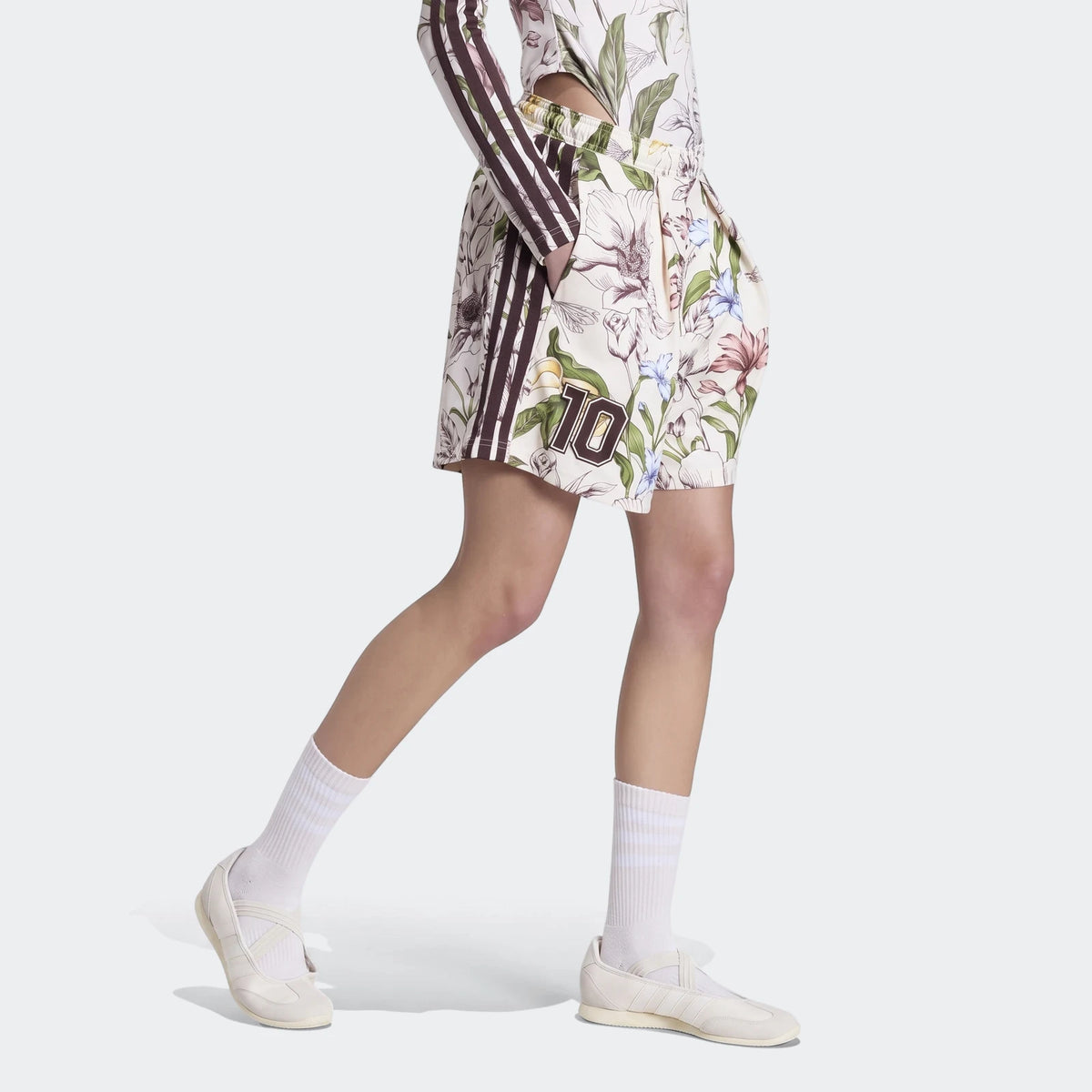 Women's X Farm Rio Premium Shorts in an off-white floral print with a brown number 10, worn by a model with white socks and