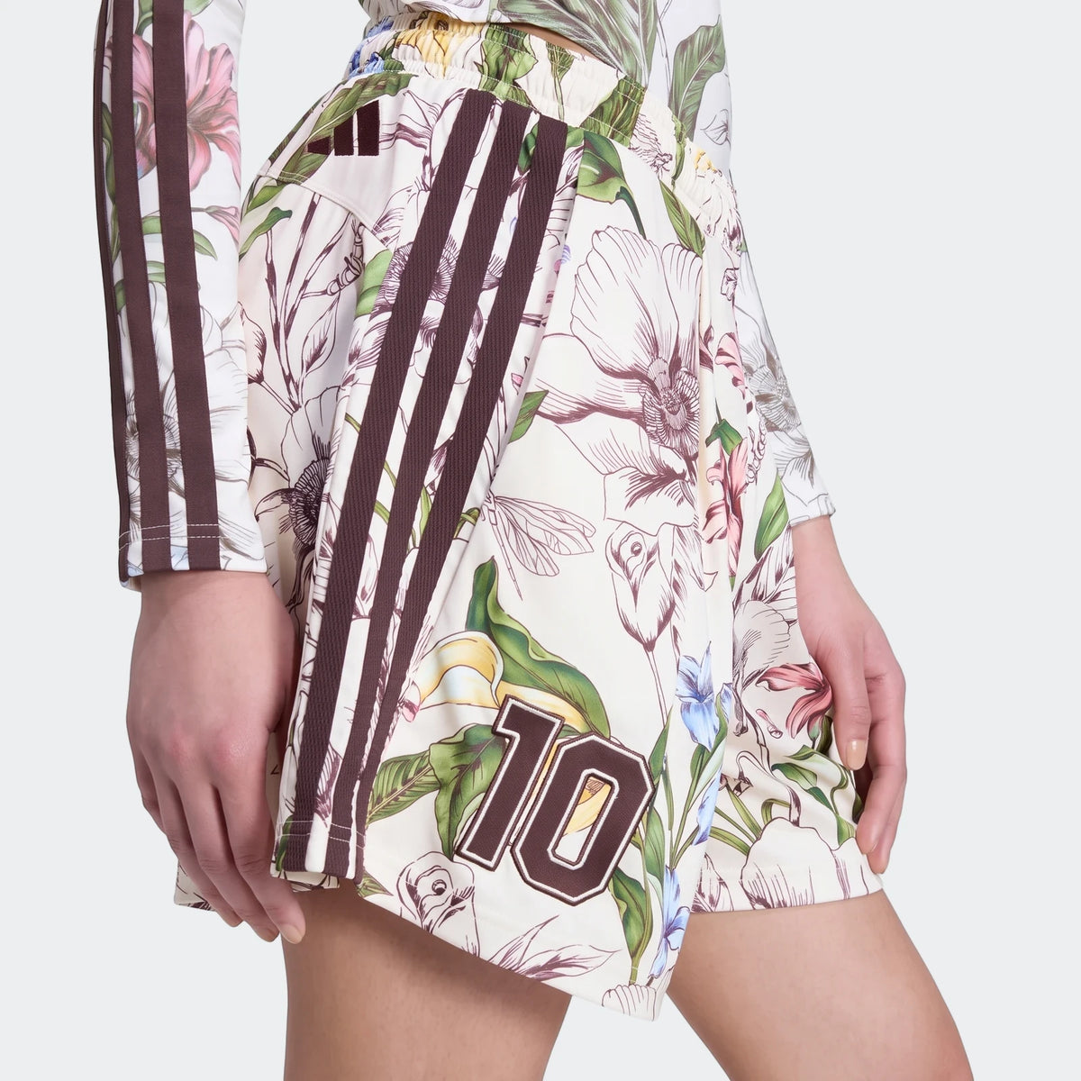X Farm Rio Premium Shorts on a model, showcasing a vibrant tropical floral print with brown Adidas three-stripes and the