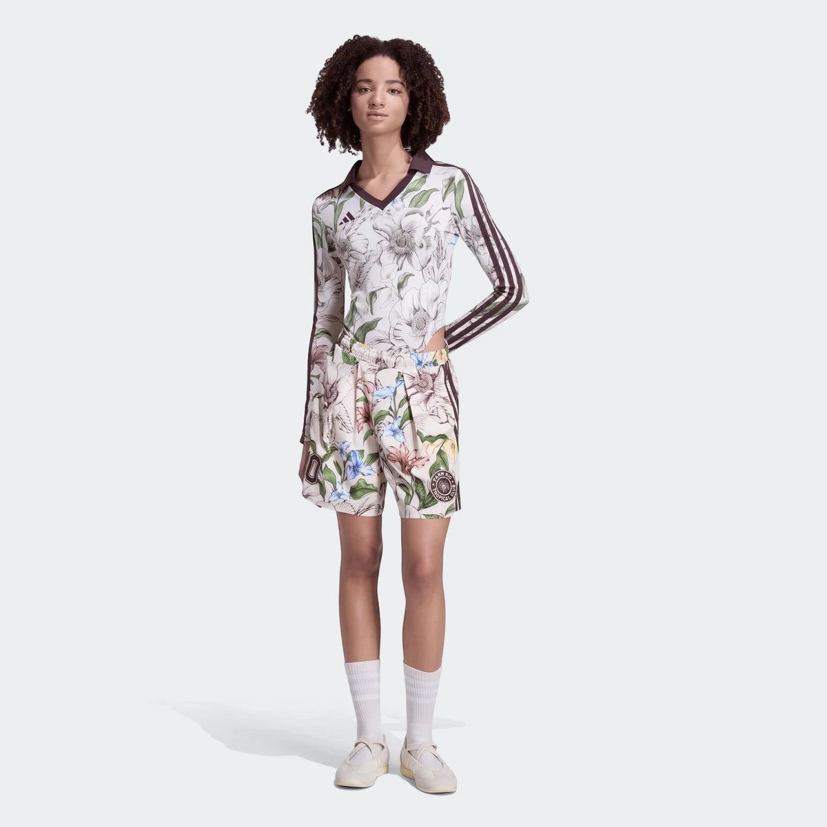 Model wearing X Farm Rio Premium Shorts with a matching long-sleeve floral print top, white socks, and light shoes.