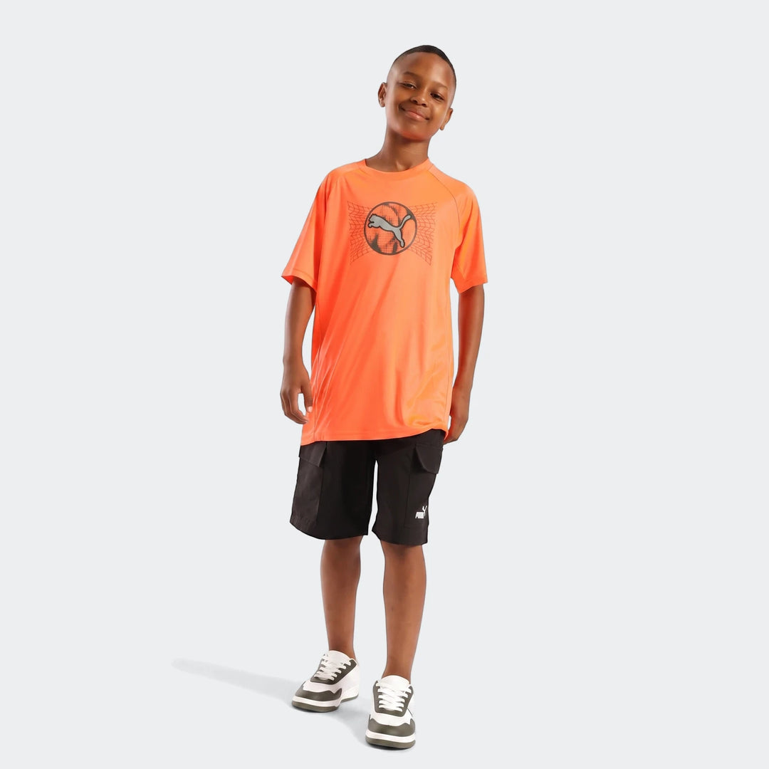 Young boy wearing an orange Puma Active Sports Graphic Tee, black cargo shorts, and two-tone sneakers, full body view.