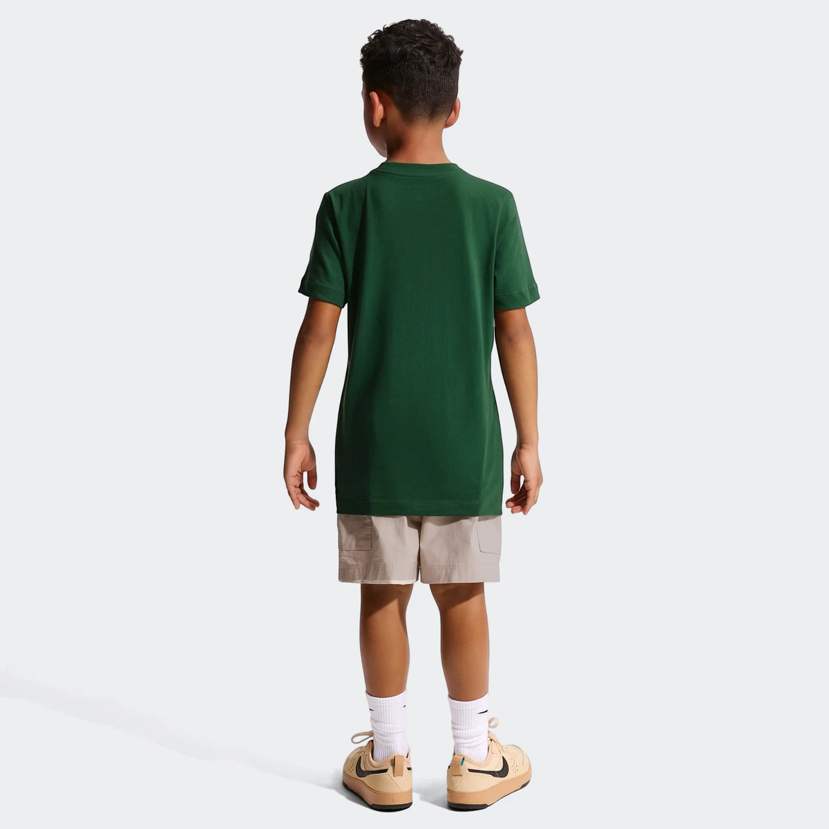 Young boy from behind wearing a dark green 2026 Nike Springboks Rugby's Greatest Rivalry Tour Kids T-Shirt with beige shorts