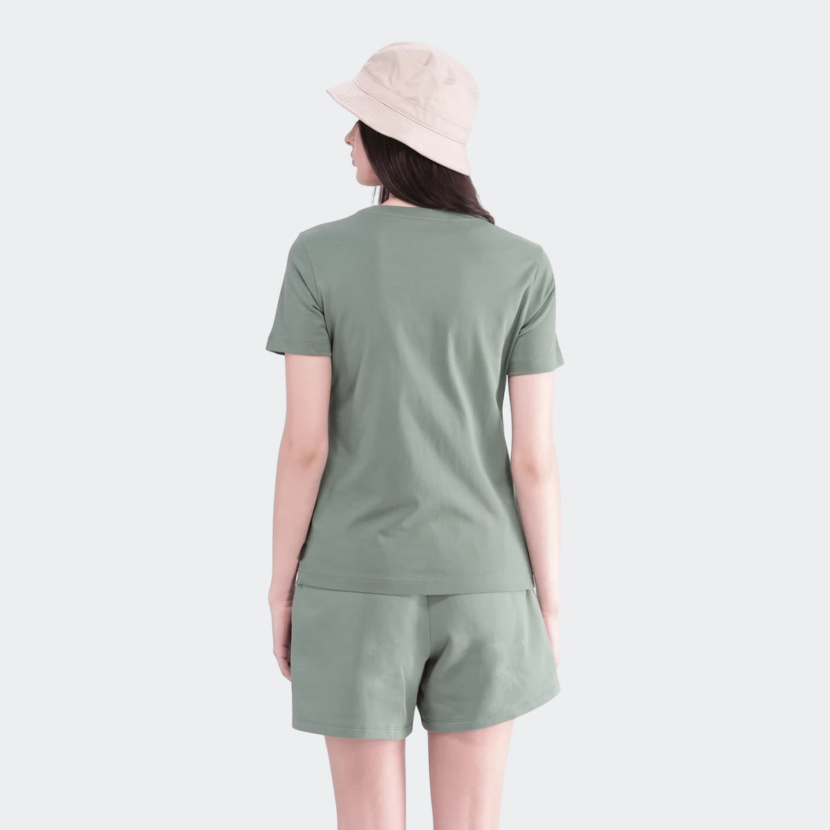 Rear view of a young woman wearing a green short-sleeve t-shirt and matching shorts set, paired with a beige bucket hat.