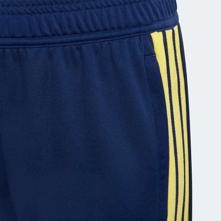 Youth Tiro 26 Competition Training Pants in dark blue, featuring three bright yellow stripes on the side, close-up detail.
