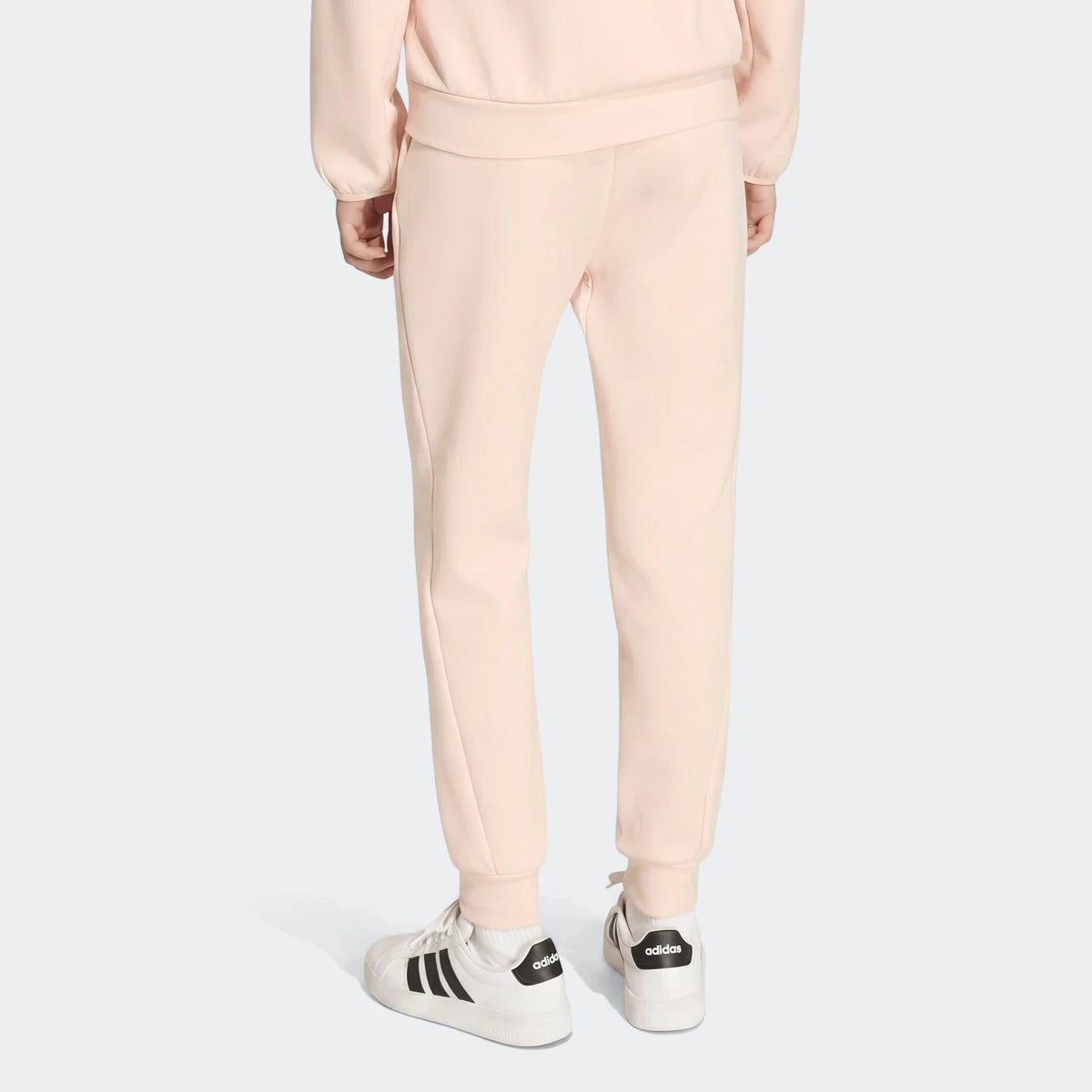 Youth Z.N.E. Track Pants in light pink, seen from the back on a model wearing white sneakers and a matching sweatshirt.