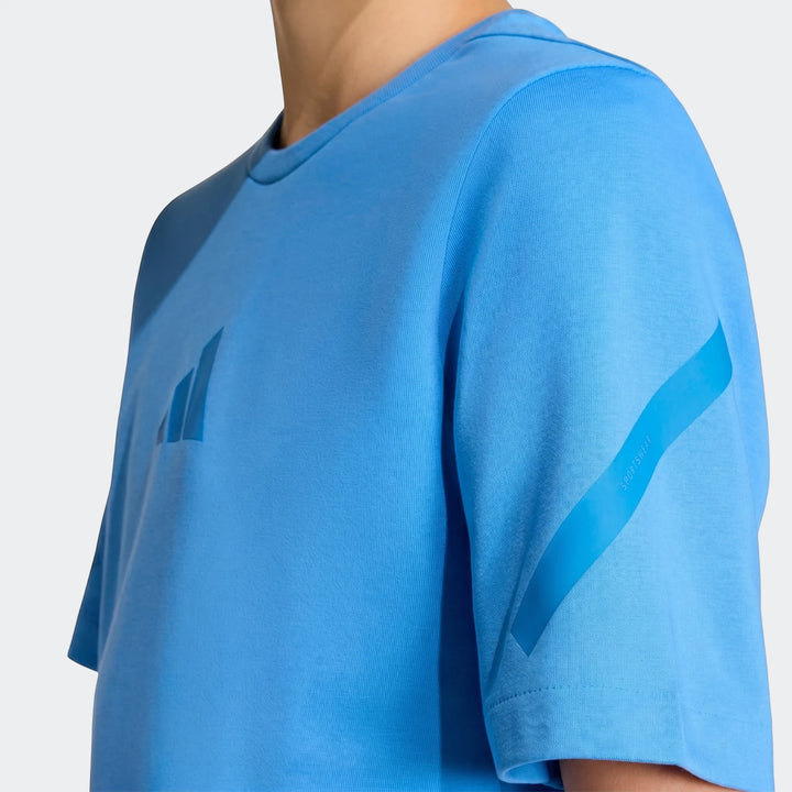 Close-up of a youth wearing a bright blue Z.N.E. T-Shirt with visible textured fabric and logo on the chest.