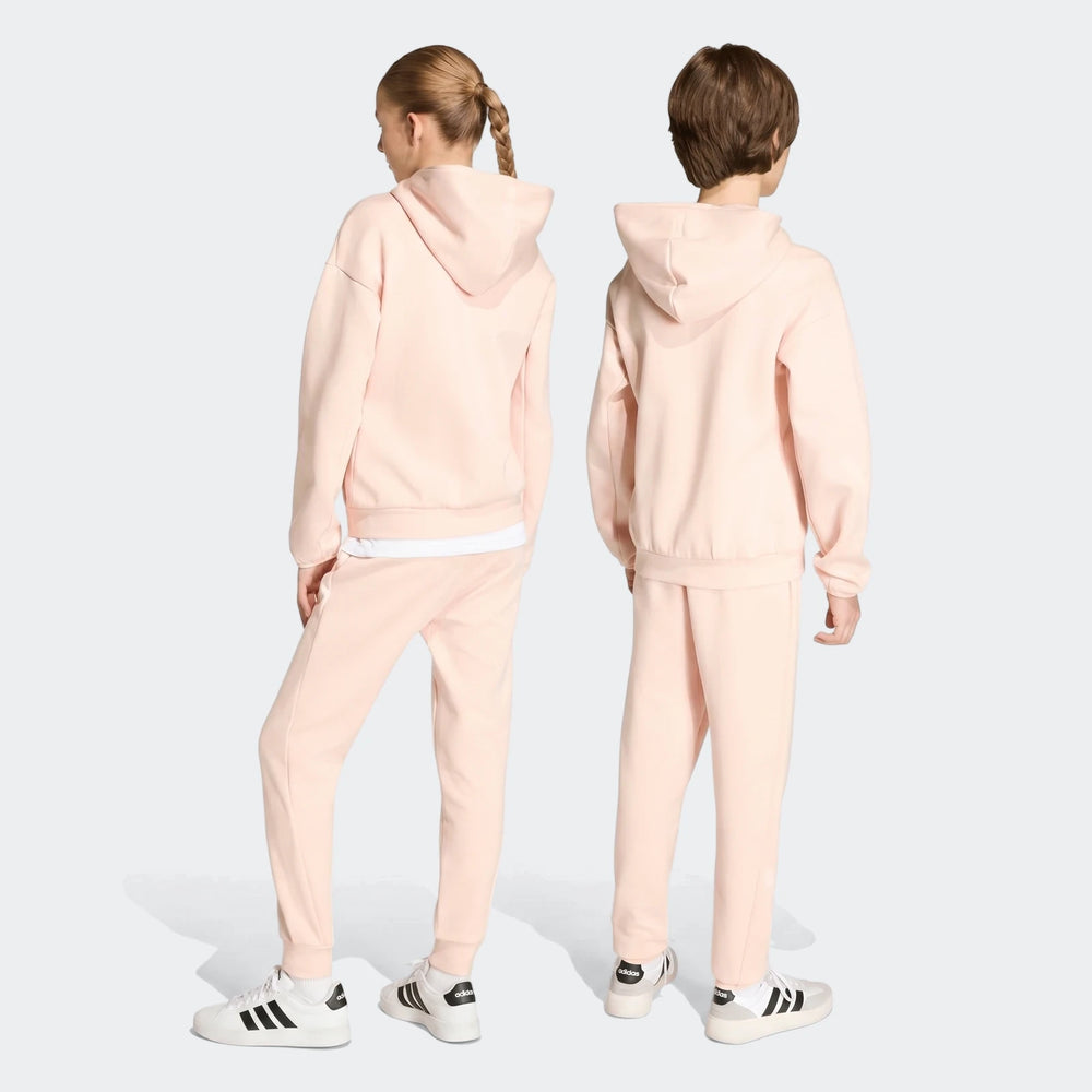 Two kids from behind wearing light pink Youth Z.N.E. Track Pants and matching hooded sweatshirts with white sneakers.