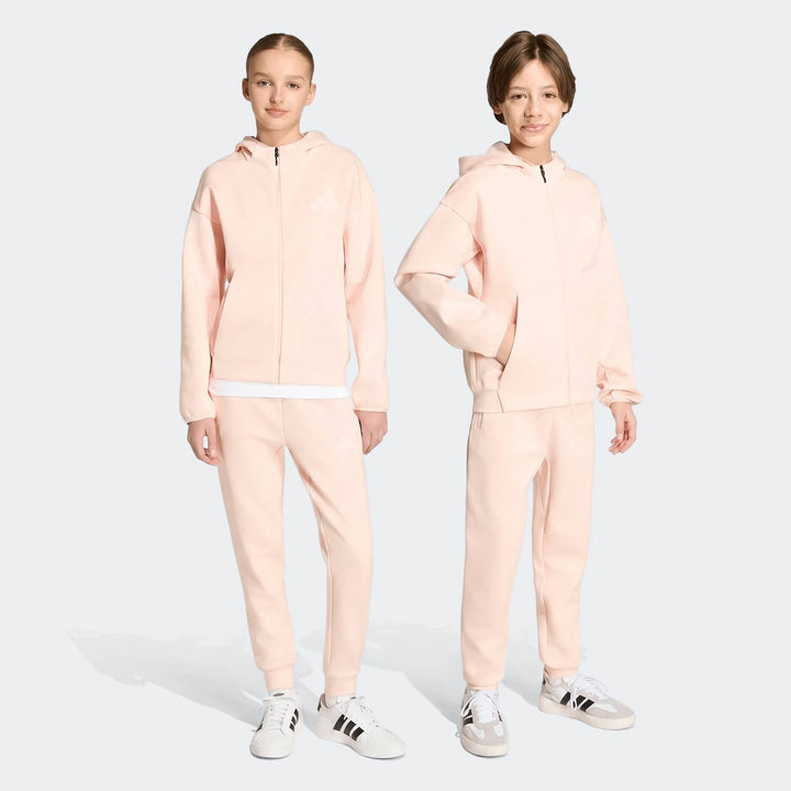 Two young individuals model pink Youth Z.N.E. Track Pants and matching full-zip hoodies, showcasing the full tracksuit.