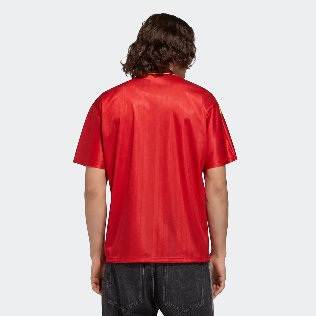 Back view of a person wearing a red short-sleeved Z.N.E. Track Top with vertical textured stripes and dark jeans.