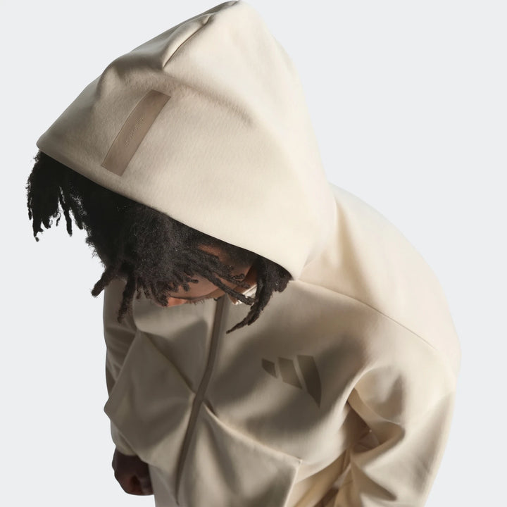 Cream Z.N.E. Full-Zip Hoodie worn by a person with dreadlocks, seen from a high-angle, upper torso view on a model.