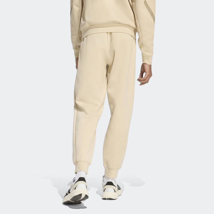 Beige Z.N.E. Track Pants worn by a model from the back, showcasing the comfortable relaxed fit and elasticated ankle cuffs.